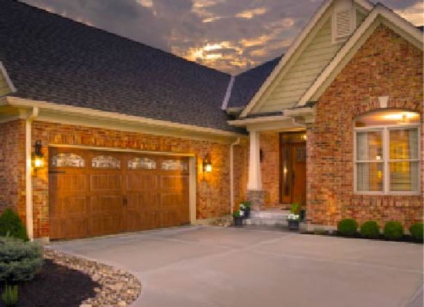 Modern contemporary house with black roof and brown wood garage doors.